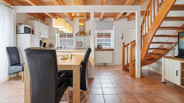 A modern kitchen with a dining area, wooden beams, and a staircase. - Wunderschönes Ferienhaus mit Eigenem Tretboot (Greetsiel)
