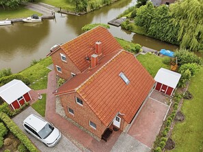 Une maison à deux étages, construite en briques, avec un toit recouvert de tuiles rouges, un garage et une allée.
