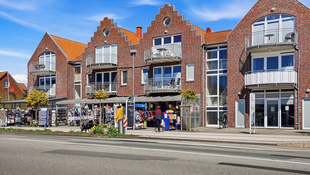 Een rij gevelhuizen van baksteen, met meerdere verdiepingen, balkons en winkelpanden.