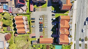 Luchtbeeld van een woonwijk met meerdere huizen, een parkeerplaats en een weg.