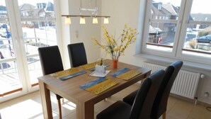 Ein Essbereich mit einem Holztisch, schwarzen Stühlen und einer Vase mit gelben Blumen.