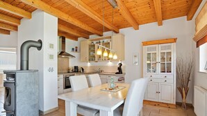Una cocina moderna con vigas de madera, estufa integrada y una zona de comedor con mesa y sillas.