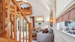 Amplia sala de estar con escalera de madera, un sofá gris y un radiador.