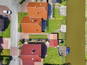 A residential area with multiple houses, a paved driveway, and a body of water. - Tolles Ferienhaus in Bestlage Direkt am Wasser (Greetsiel)