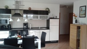 Una cucina moderna con mobili bianchi, piani di lavoro neri e un'area pranzo con tavolo apparecchiato per due.