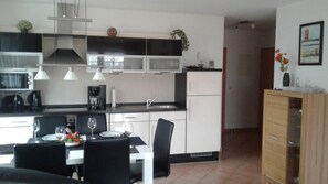 A modern kitchen with white cabinets, black countertops, and a dining area with a table set for two.