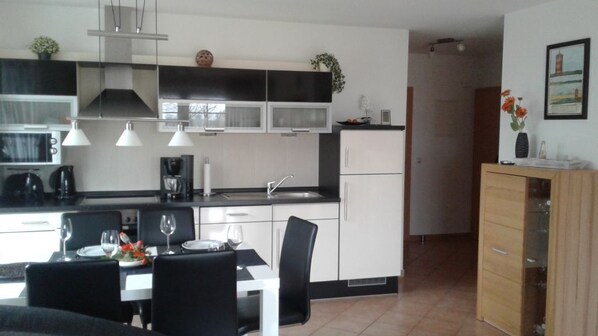 A modern kitchen with white cabinets, black countertops, and a dining area with a table set for two.