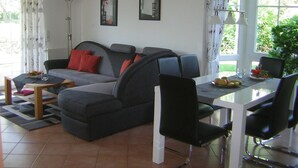 Un soggiorno moderno con un divano grigio, poltrone nere, un tavolo da pranzo in vetro e una lampada da terra.