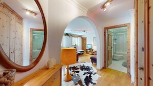Um interior moderno com piso de madeira, um espelho grande, um tapete de couro e um box de chuveiro envidraçado.