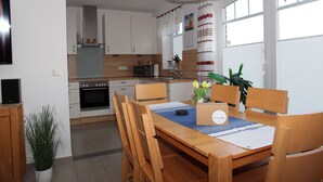 Uma cozinha moderna com armários de madeira, forno embutido e uma área de jantar com mesa e cadeiras de madeira.