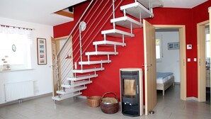Um interior moderno com parede vermelha, escada branca e lareira a lenha.