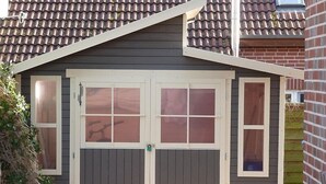 Garagem para dois carros com telhado empena e porta com janela.