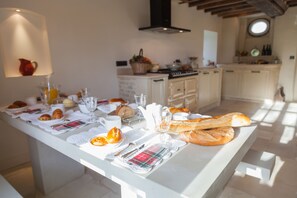 A breakfast setup with croissants, orange slices, and a glass of orange juice on a table.