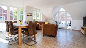 Ein geräumiger Wohnbereich mit Esstisch, Stühlen, einer Couch und einem Fernseher.