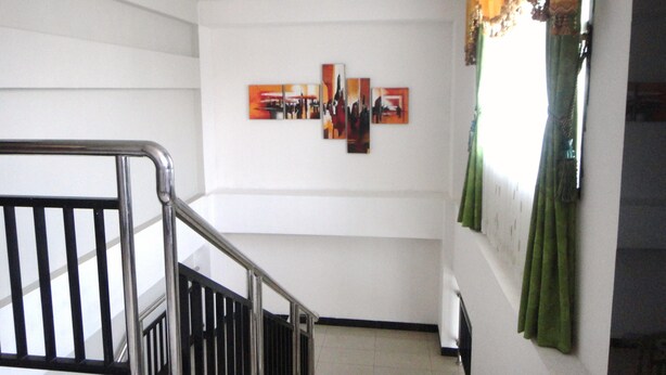 A staircase with a metal railing leading to a landing. There are three framed artworks on the wall above the staircase.