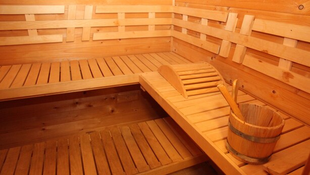 Een houten sauna met banken en een houten emmer.