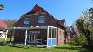 Een huis van baksteen met twee verdiepingen, een overdekte patio, een zichtbaar raam en een kleine tuin.
