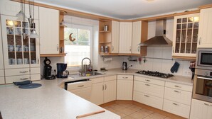 Een keuken met witte kasten, een gasfornuis, een magnetron en een spoelbak.
