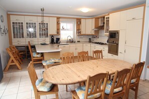 Une cuisine spacieuse dotée de meubles en bois, d’un îlot central et d’un coin repas avec des chaises en bois.