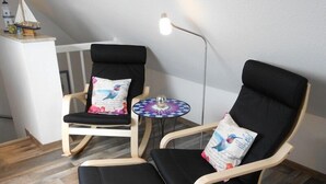 Un rincón amoblado con dos sillones negros acolchados y una mesita redonda con cubierta a cuadros.