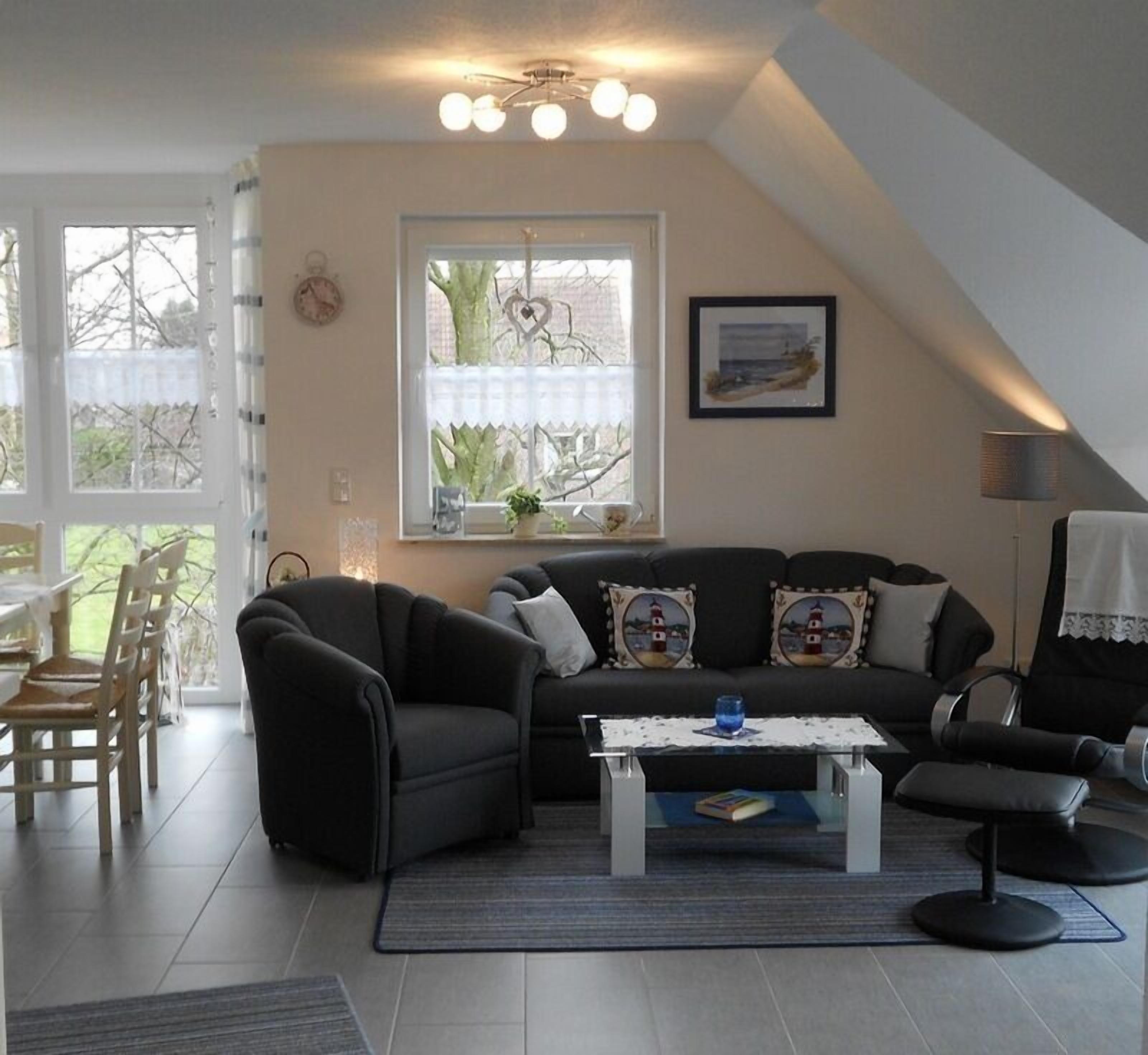 A modern living room with a black sofa, a coffee table, and a dining area with chairs.