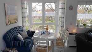 Una sala de estar acogedora con un sofá azul, una mesa de comedor con sillas y un sillón oscuro.