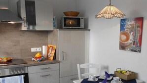 Una cocina moderna con microondas, horno y comedor con mesa preparada para dos.