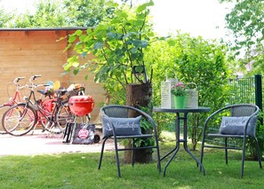 A patio with two wicker chairs, a small table, and a barbecue grill. - Sehr Schöne Ferienwohnung in Zentraler und Ruhiger Lage (Greetsiel)