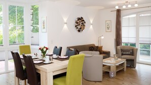 A modern living room with a dining area, featuring a wooden table, green and brown chairs, a sofa, and a coffee table. - Sehr Schöne Ferienwohnung in Zentraler und Ruhiger Lage (Greetsiel)
