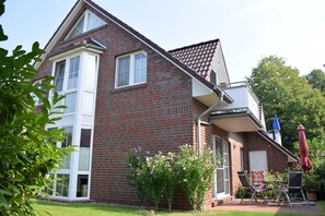 A two-story brick house with a covered patio, a window, and a door.