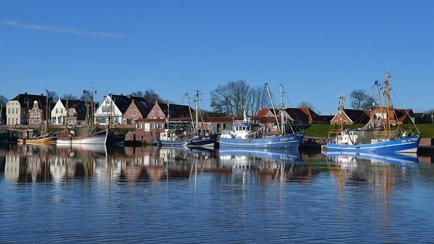 A harbor with boats docked and houses along the water. - Erdgeschosswohnung "godewind" Zentral in Greetsiel (Greetsiel)