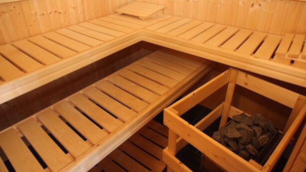 Un sauna avec des bancs en bois et un récipient rempli de pierres.