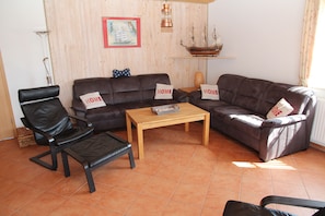 Ein Wohnzimmer mit einem braunen Ledersofa, einem Holztisch und einem schwarzen Ledersessel.
