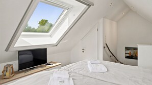 A bedroom with a skylight, a bed, a TV, and a painting on the wall. - Wunderschöne Ferienwohnung im Ortskern (Greetsiel)