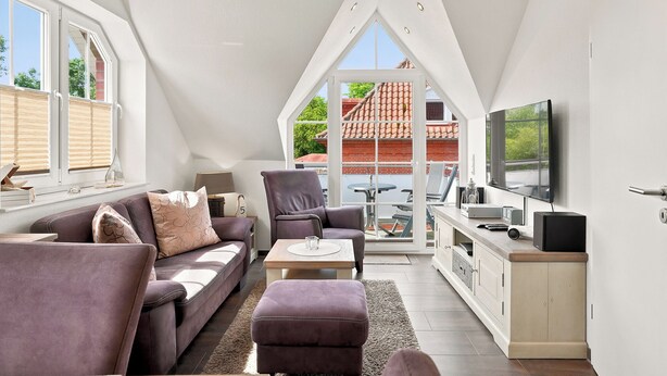 A modern loft apartment with a high ceiling, large windows, a flat-screen TV, and a cozy seating area. - Wunderschöne Ferienwohnung im Ortskern (Greetsiel)
