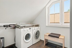 Ein Waschraum mit Waschmaschine, Wäscheständer und einem kleinen Holzschrank.