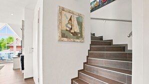 A staircase with wooden steps and a painting of a sailboat on the wall. - Wunderschöne Ferienwohnung im Ortskern (Greetsiel)
