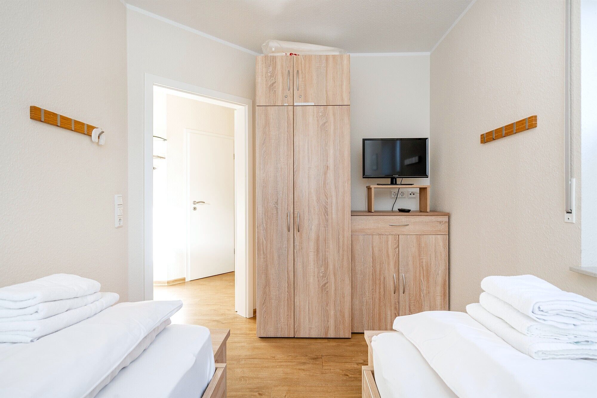 Camera d'albergo con due letti, una TV e un armadio in legno.