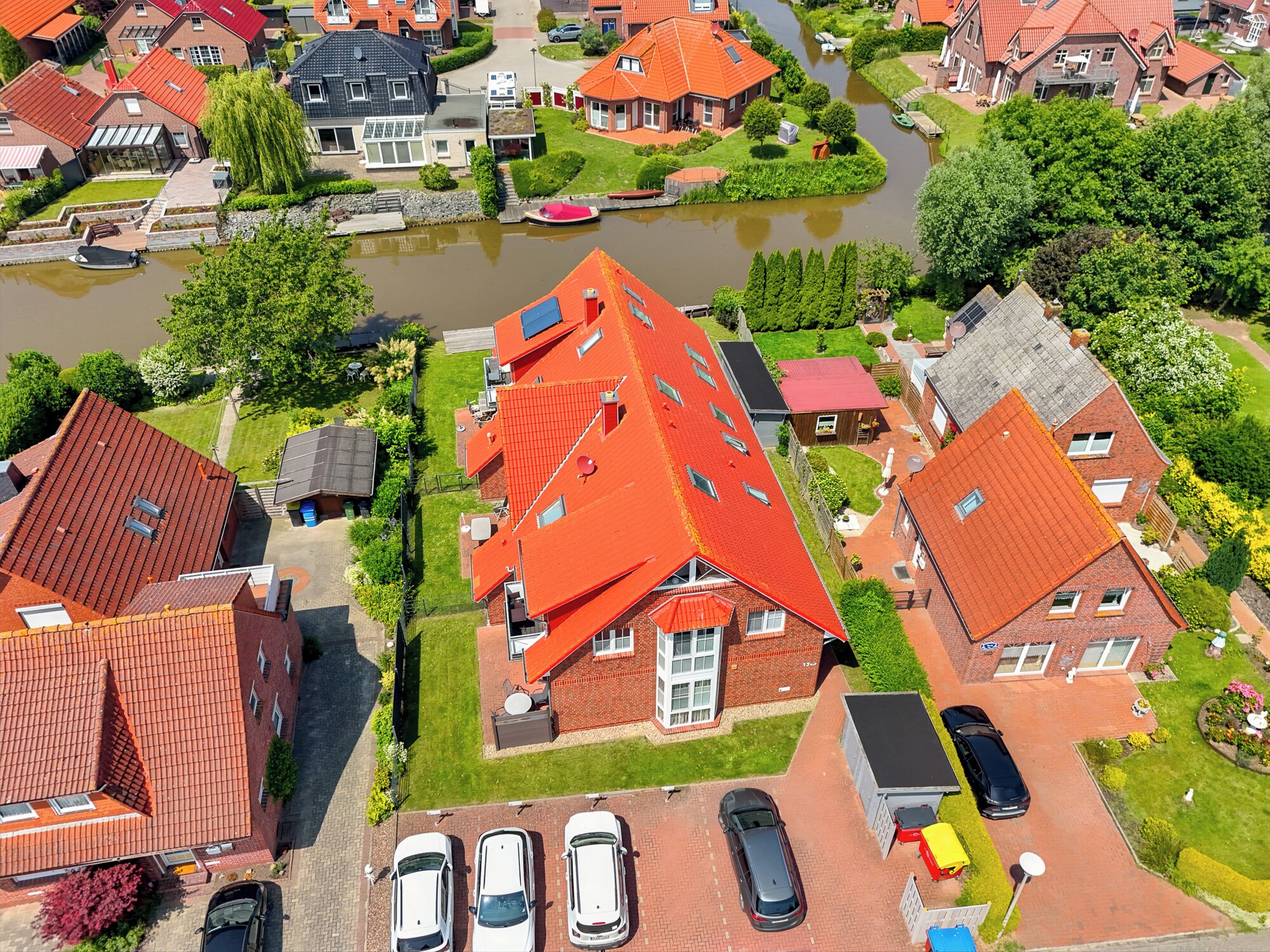 Eine Luftaufnahme eines Wohngebiets mit Häusern, einem Fluss und geparkten Autos.