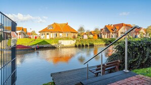 A canal with houses on one side and a metal railing in the foreground. - Schöne Ferienwohnung in Wassernähe (Greetsiel)