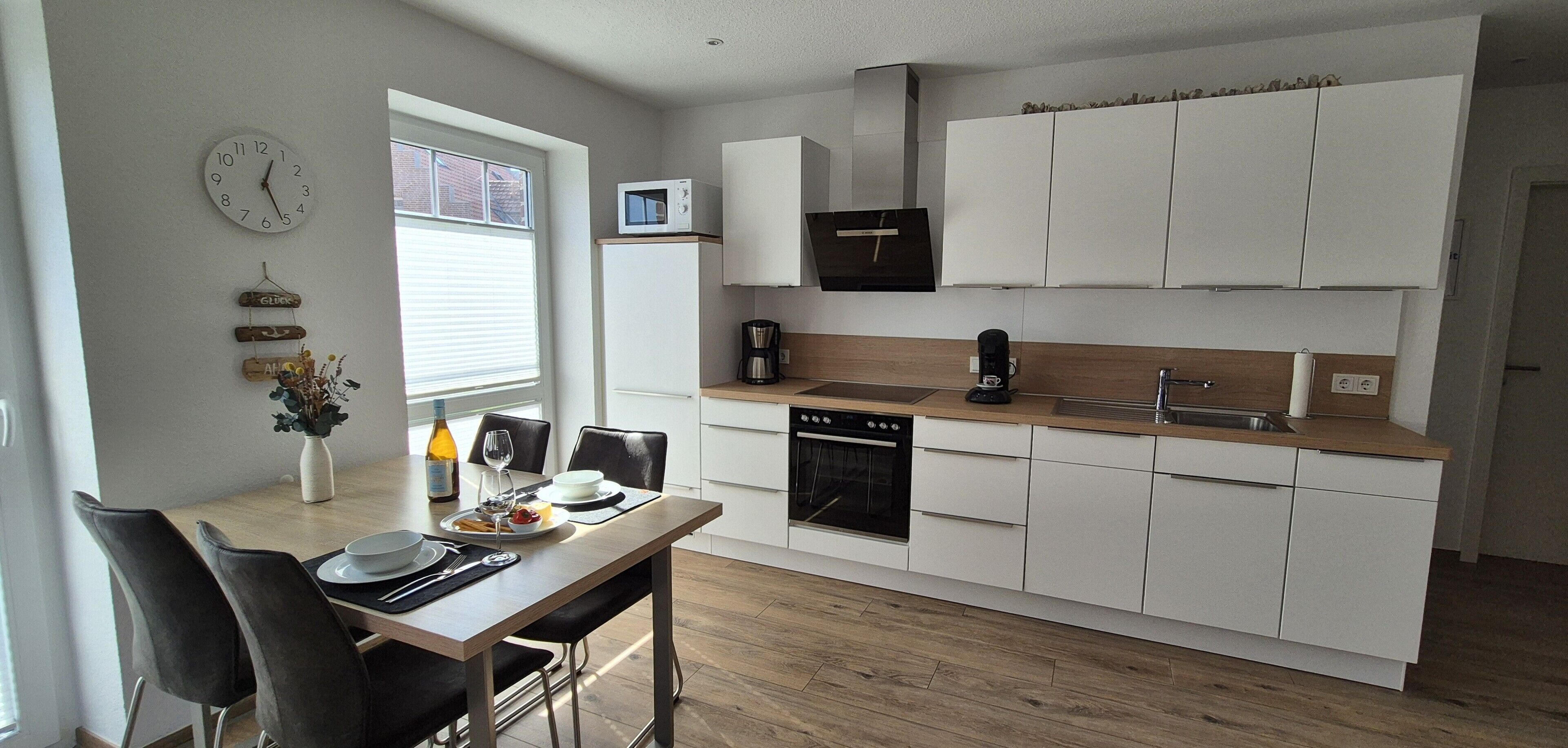 A modern kitchen with white cabinets, a built-in oven, and a microwave.