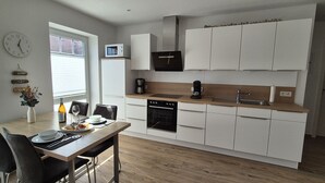 Een moderne keuken met witte kasten, een ingebouwde oven en een magnetron.