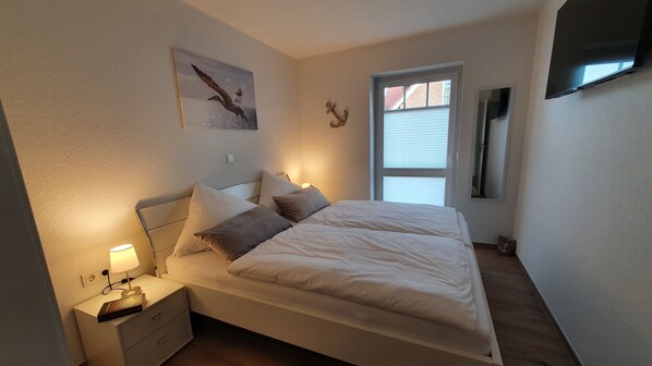 Une chambre à coucher avec un lit, une table de chevet, une lampe et une fenêtre.