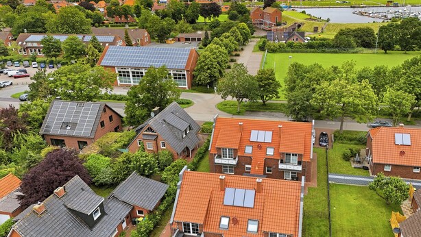 A residential area with houses, solar panels, and a body of water. - Zentral Gelegene Ferienwohnung in Greetsiel (Greetsiel)