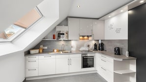 Una cocina moderna con armarios blancos, un tragaluz y un horno empotrado.