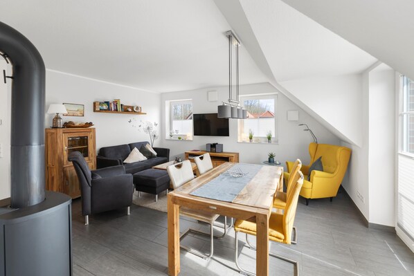 A modern loft with a dining area, sofa set, and a yellow armchair.