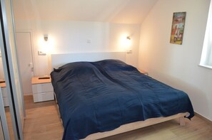 Quarto com cama, mesas de cabeceira e luminárias na parede.
