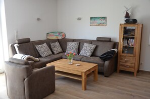 Uma sala de estar com um sofá marrom, uma mesa de centro de madeira e um armário com livros.