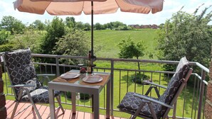 Un patio con una mesa, sillas y una sombrilla.