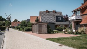 Une rue bordée de maisons, avec un moulin à vent et une petite construction en bois.